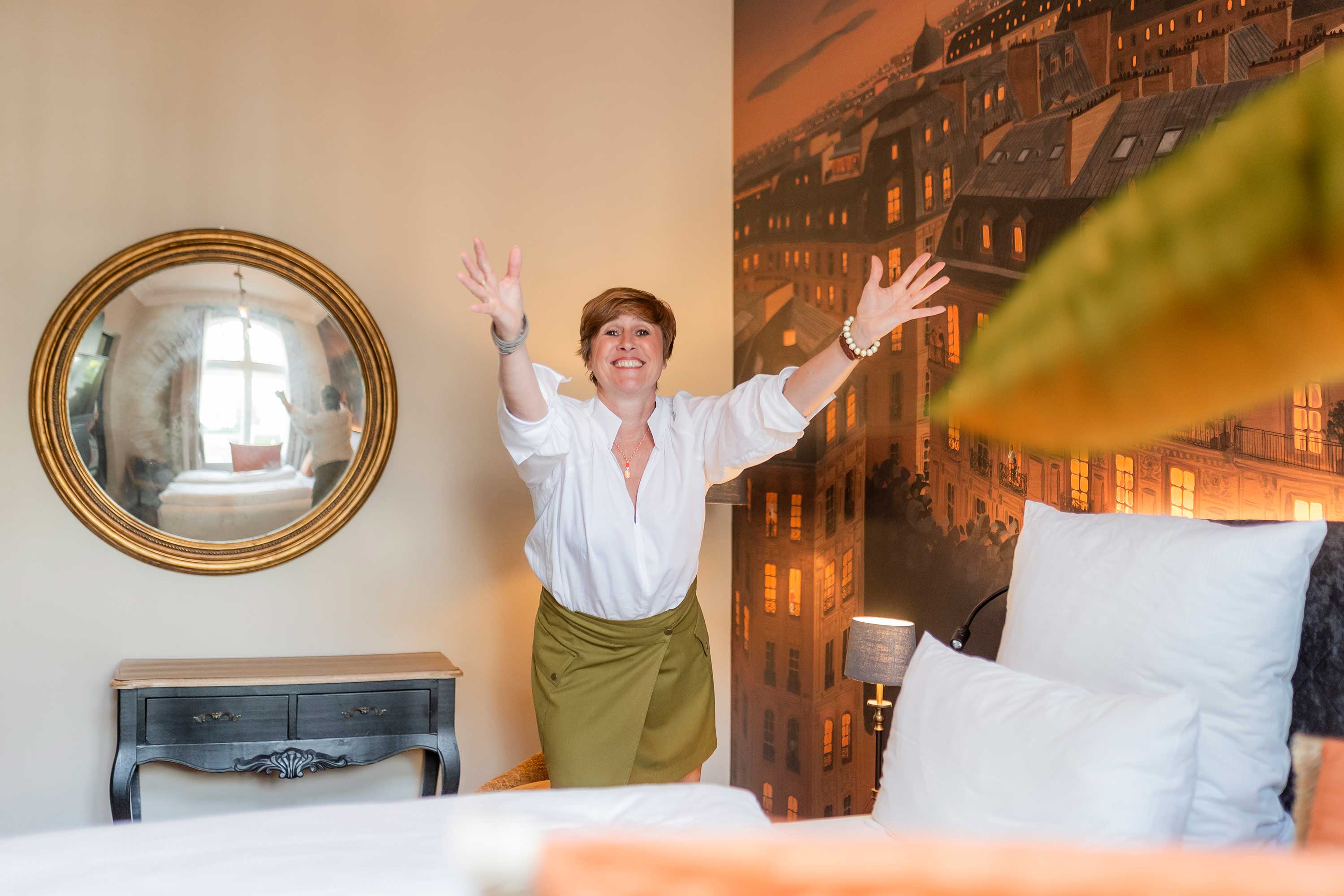 Ulrike Jaitner mit ausgebreiteten Armen in einem Hotelzimmer